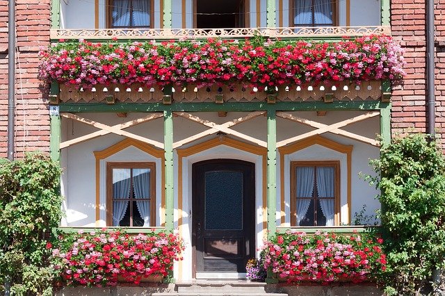 Dom s balkónom s dreveným zábradlím a množstvom kvetov
